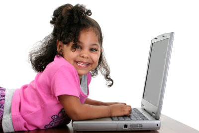 Three-year-old toddler girl in pink playing with a laptop computer